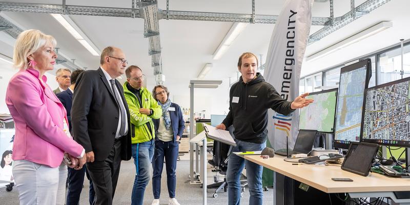 Serveral people stand in front of monitors