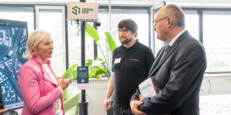 Three people discussing in front of a Heinerbox