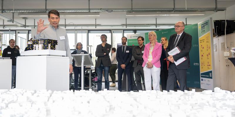 A man in front of a small model of the eHUB talks to an audience