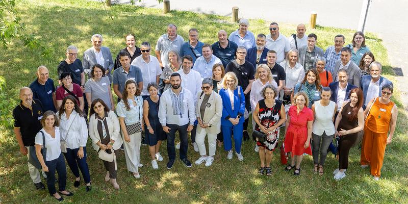 A group photo of about 50 people, taken from above on a green lawn.