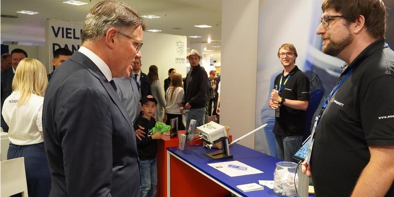 Drei Menschen stehen an einem Stand.