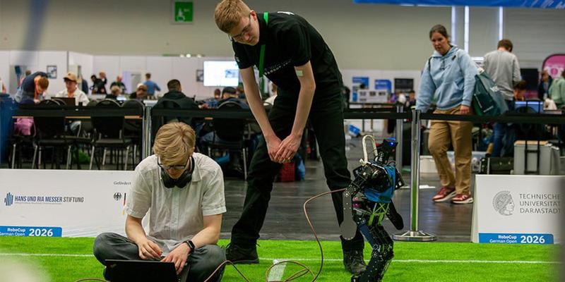 Two scientiests with a walking robot in front of an audience