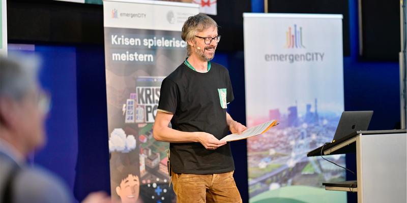 A man standing on a stage in front of people smiling
