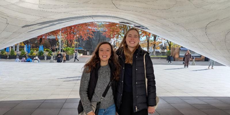 Two women under a silver statue