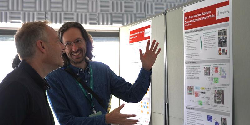 One man explains his research to another using his poster.