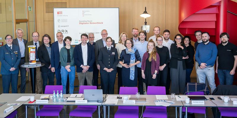 Gruppe von Menschen stellt sich für Erinnerungsfoto vor einer Präsentation auf.